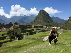 Photo of study abroad student Brianna Rivera kneeling on the grass in Peru.